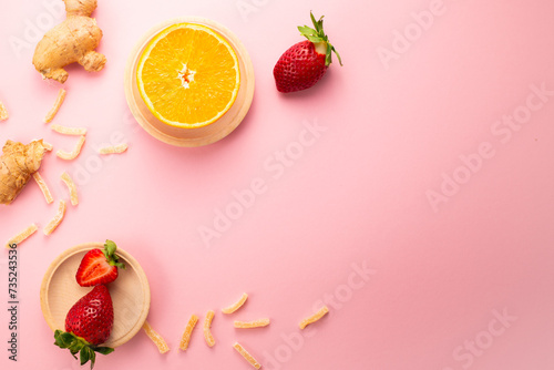 Fototapeta Naklejka Na Ścianę i Meble -  Ginger in sugar, strawberries and orange on pink background. Gourmet oriental sweets. Flat lay. Copy space