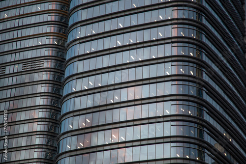 Close up of the facade of a modern office building. The city buildings view with the reflection on the glass windows at the sunset