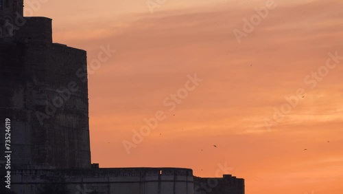 dusk sky shot showing birds flying around the majestic stone walls of mehrangarh fort with monsoon clouds showing this famous tourist spot and a part of rajput history photo