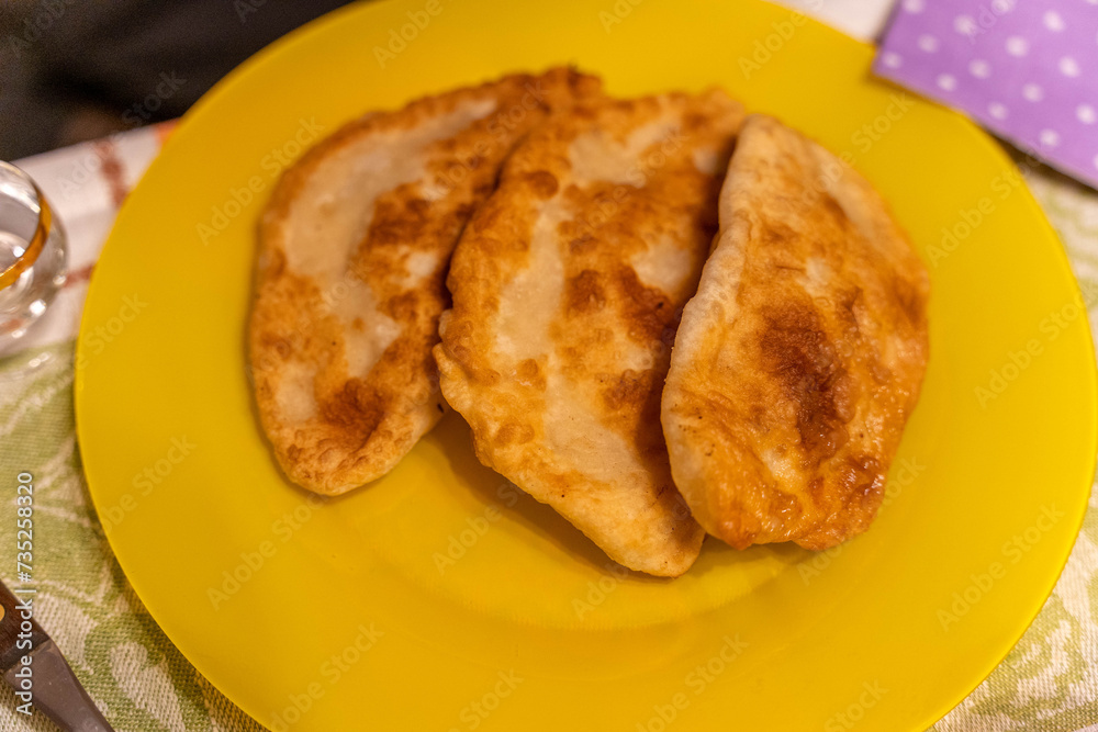 Fried Chebureks with meat on a yellow plate. Traditional food.