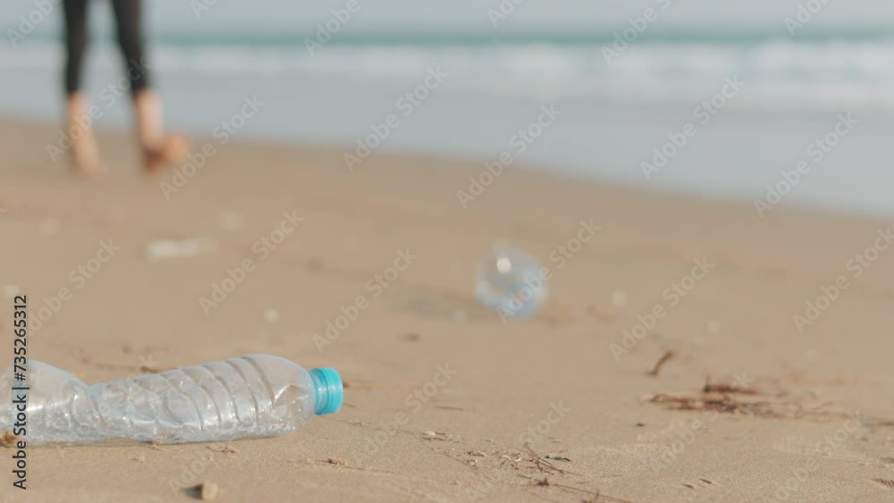Close up of abandoned PET plastic bottle on the sand and kid picking it to clean the beach for recycle shows concept of people helping to preserve the cology from pollution and global warming issues. Close up of abandoned PET plastic bottle on the sand and kid picking it to clean the beach for recycle shows concept of people helping to preserve the cology from pollution and global warming issues.