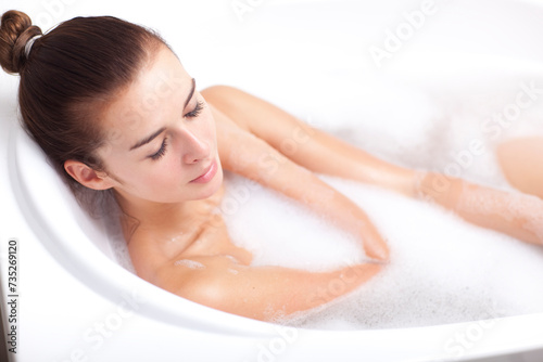 A young woman takes a bath in a bathtub full of foam.