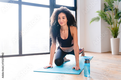 Home training concept. Caucasian young female athlete, strong flexible sportswoman in fitness clothes stretching on mat. Stamina, training, body shaping