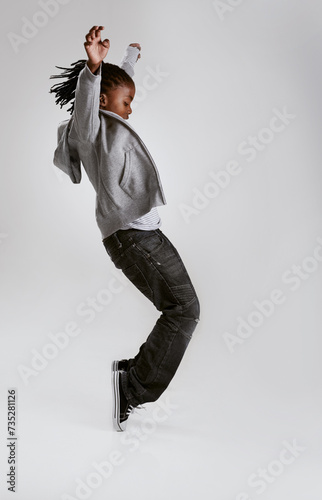 Kid, fashion and dance with energy in studio with hoodie in streetwear on grey background. African, child and cool teenager or dancer with casual style, clothes and balance on shoes in mockup photo