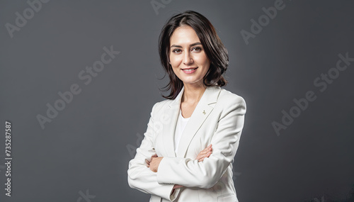 Portrait of a smiling businesswoman in white suit on grey background