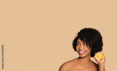 Joyful black woman with fresh lemon for skincare