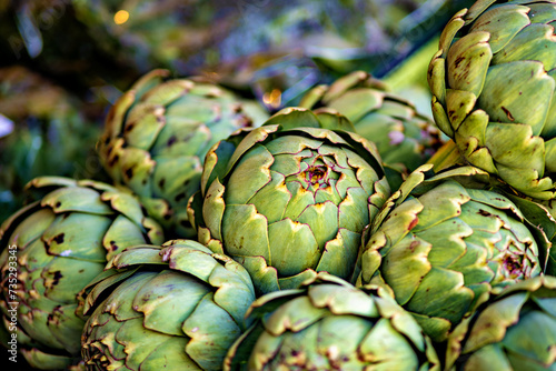 Bunch of green artichokes sitting on top of each other. photo