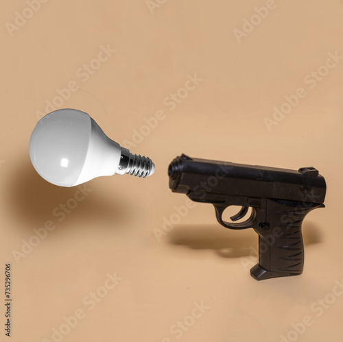 Pistol and light bulb creative concept. Electricity prices going up.  photo