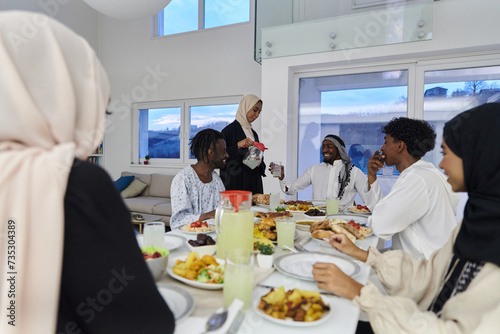 In the sacred month of Ramadan, a Muslim family joyously comes together around a table, eagerly awaiting the communal iftar, engaging in the preparation of a shared meal, and uniting in anticipation © .shock