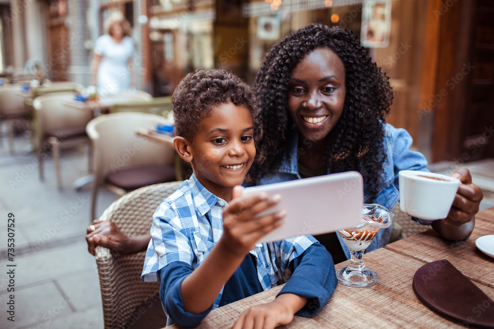 Smiling mother sitting in public cafe with son taking selfie Smiling mother sitting in public cafe with son taking selfie