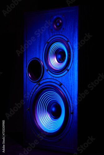 Sound speaker in neon light. Modern hi-fi loudspeaker against black background. Sound audio equipment with neon lights. Dynamic sub monitor close up. Creative backgroound