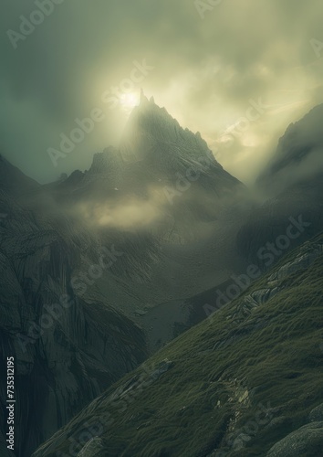 a mountain covered in green grass under a cloudy sky with the sun peeking through the clouds over the top of the mountain. photo