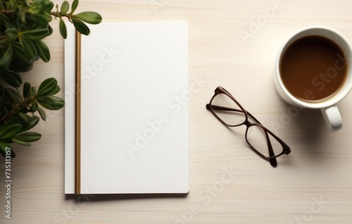 a coffee cup, notebook, and glasses next to a blank page