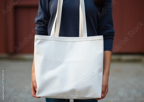 a woman holds up her blank, white tote bag