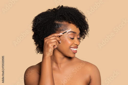 Happy african american woman grooming eyebrows with brush