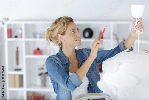 woman installing new ceiling light in her home