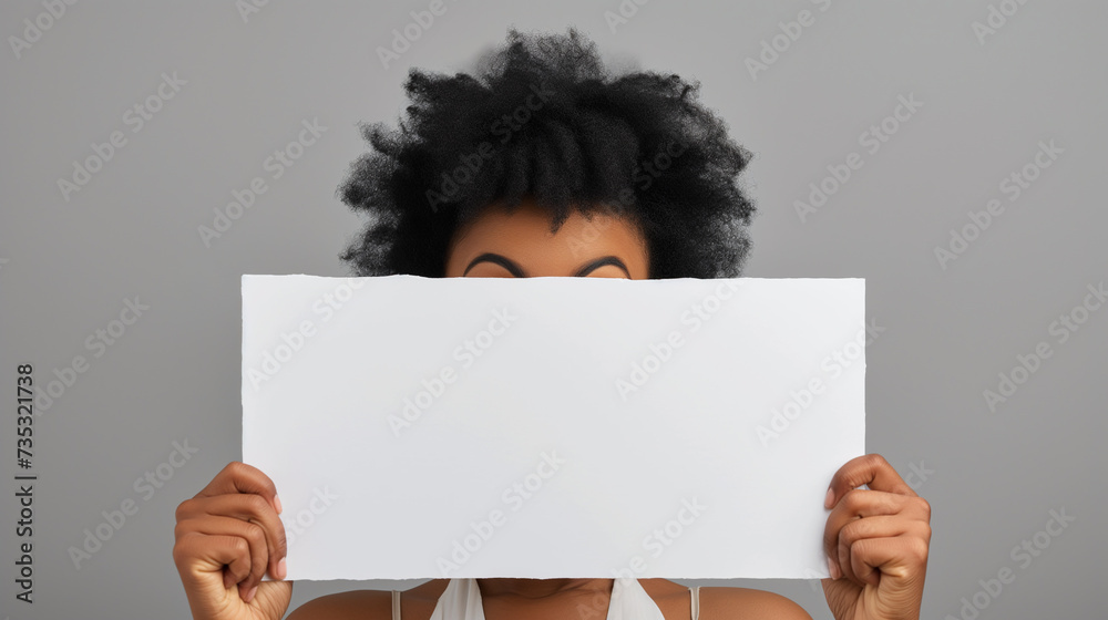 Mulher afro-americana surpresa espiando por trás de um outdoor em branco - obrazy, fototapety, plakaty 