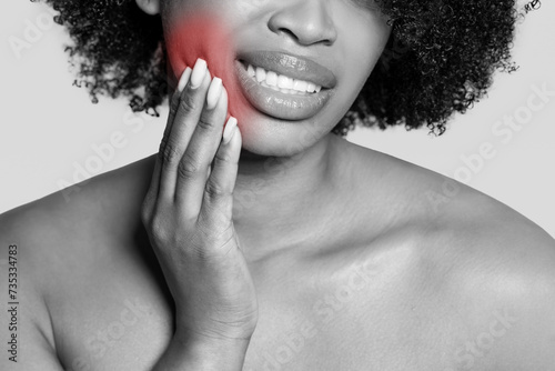 Young woman holding cheek in pain, toothache highlighted in red photo