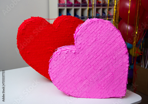 red and pink heart on wooden table, heart shaped pinatas