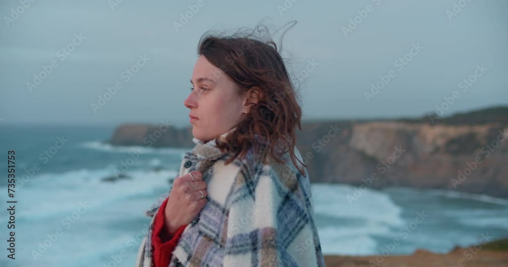 Moody nostalgic woman deep in her thoughts gets wrapped in jacket on cold windy day, look away into distance on amazing landscape. Moody nostalgic woman deep in her thoughts gets wrapped in jacket on cold windy day, look away into distance on amazing landscape.