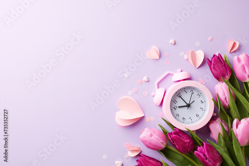 Embrace the blossoming love: springtime greetings to my beloved.Top view of a bouquet of fresh tulips, alarm clock, tender hearts on lilac background with space for greetings or promo