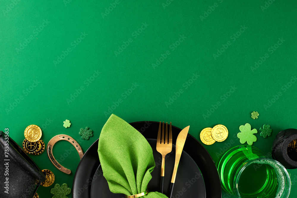 Fototapeta premium St. Patrick's Day сelebration: уmbracing irish serving traditions. Top view of coins, horseshoe, napkin elegantly folded with a ring, plates, cutlery on green background with space for advertising