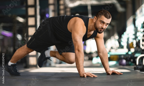 Motivated Muscular Man Making Running Plank Exercise While Training In Gym