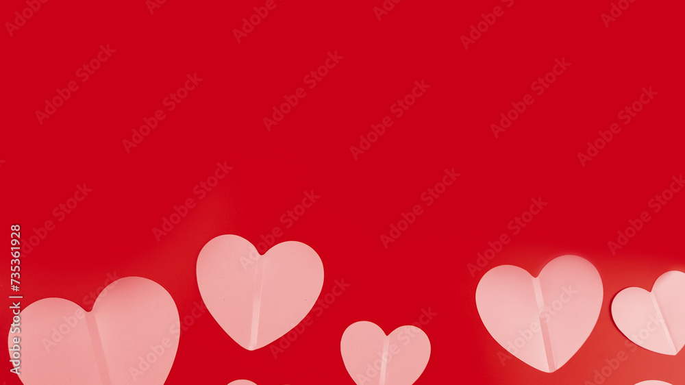 Top view of table decoration concept for Valentine's Day background. Paper cut hearts on a red background, space for text. Several objects on red wallpaper.