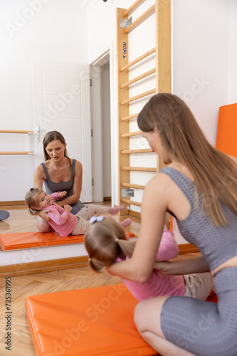 Young woman and the toddler daughter exercising together in the gym