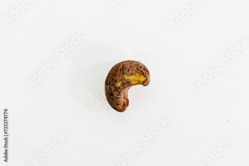 Close Up Shot of a single Dirt Weathered Cashew on a White Table Surface, Abstract Food Background and Wallpaper