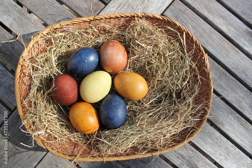 Naturally colored Easter eggs in a basket on a meadow