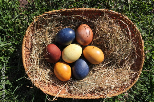 Naturally colored Easter eggs in a basket on a meadow