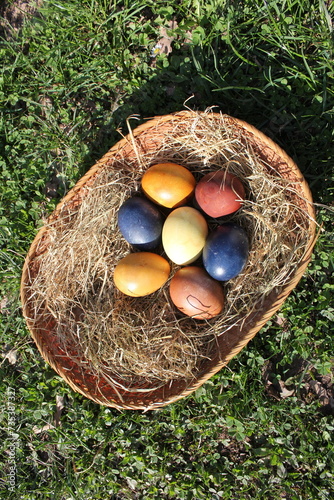 Naturally colored Easter eggs in a basket on a meadow