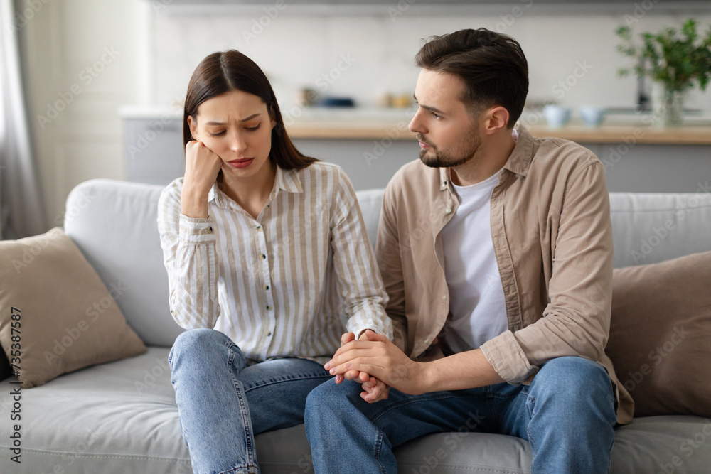 Concerned young man comforting upset woman on couch Concerned young man comforting upset woman on couch
