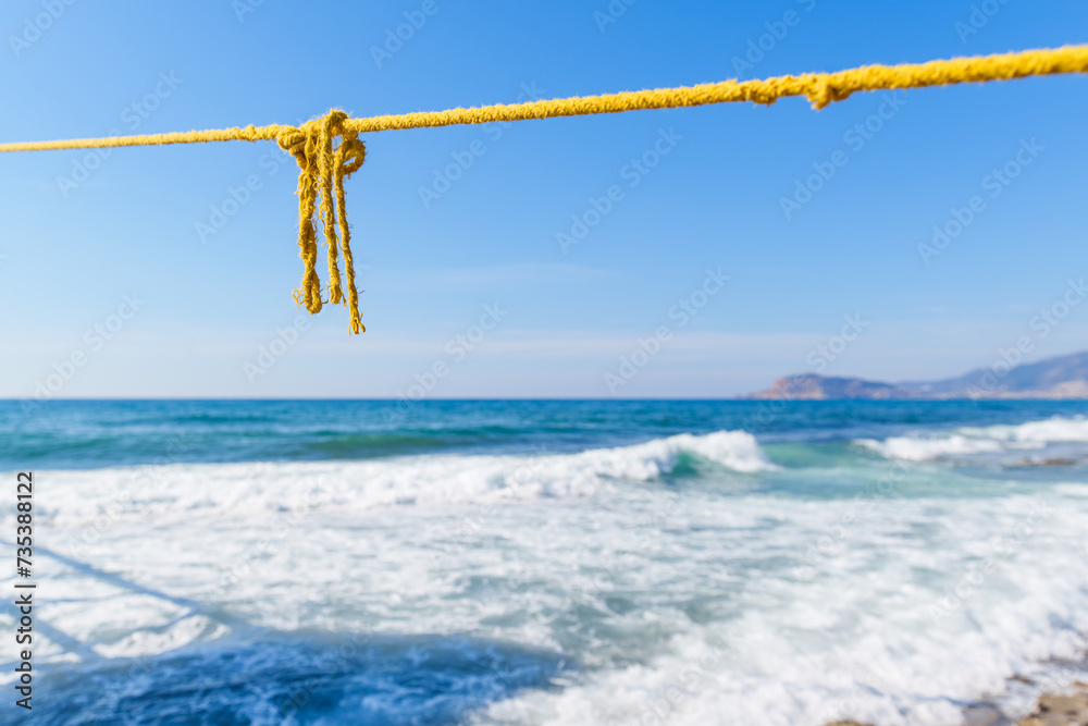 Naklejka premium Rope String knot Hanging on a Wooden Boardwalk Bay at a Sandy Beach Infront of the Blue Sea and Sky