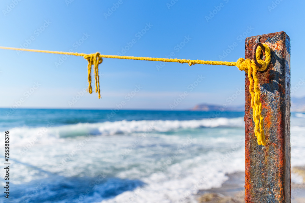 Naklejka premium Rope String knot Hanging on a Wooden Boardwalk Bay at a Sandy Beach Infront of the Blue Sea and Sky