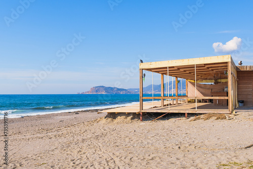 Empty Abandoned Wooden Cottage Cafe On a Sandy Beach next to the Blue Sea and Ocean waves during a Sunny Summer day  Alanya Castle