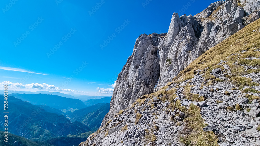 Panoramic view of majestic mountain cliff Schartenspitze in untamed Hochschwab mountain region, Styria, Austria. Scenic hiking trail in shadows in remote Austrian Alps. Wanderlust in alpine summer