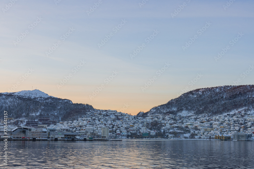 South part of bay of Bergen in early morning of winter. Sun slowly rising behind the mountains revealing suburbs of Laksevåg and Damsgard