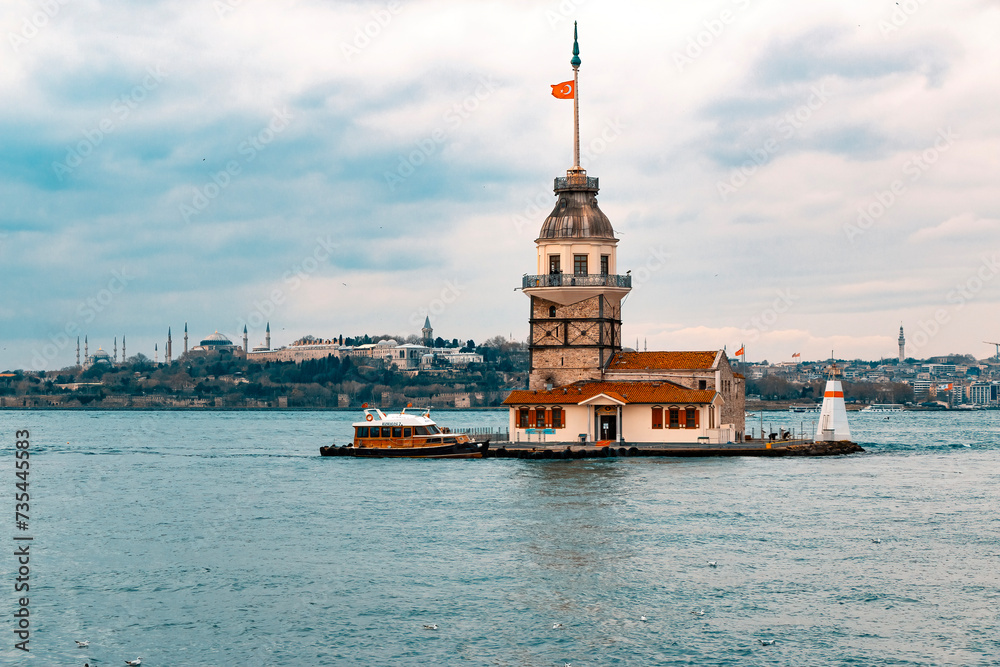Fototapeta premium Maiden's Tower (Kız Kulesi), the famous symbol of Turkey, on the Bosphorus. View of the Bosphorus and the Maiden's Tower with a cloudy blue sky on a sunny day.