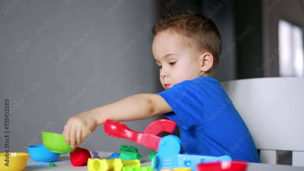 Cute Caucasian baby playing peacefully at home. Lovely baby boy dealing with plasticine and bright toys on his desk. Cute Caucasian baby playing peacefully at home. Lovely baby boy dealing with plasticine and bright toys on his desk.
