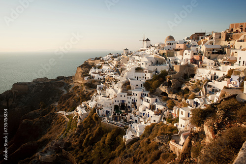 Santorini at Golden Hour: Cliffside View with Iconic Windmills. Postcard View from Greece.   © NILSEN Studio
