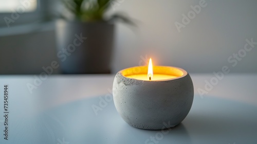 A concrete candlestick rests elegantly on a white surface, emanating a sense of modernity and refined simplicity. Luxury elegant decoration with soft candle flame. photo