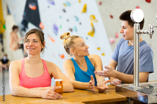 Two sports women and a guy drink tea or coffee after training at the climbing wall