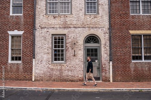 Stylish Man Walking Down a Street in Front of a Dual Colored Brick Facade in Historic Williamsburg Virginia