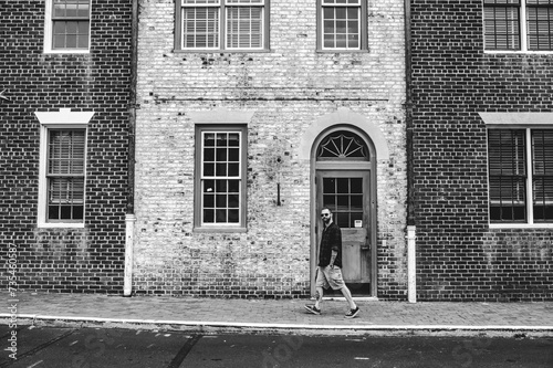 Stylish Man Walking Down a Street in Front of a Dual Colored Brick Facade in Historic Williamsburg Virginia