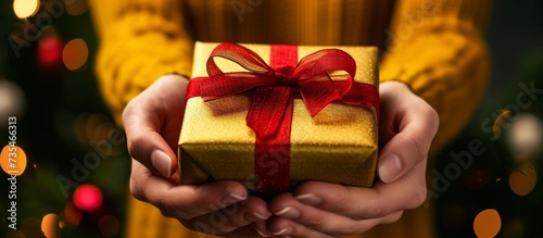 Joyful person holding a beautifully wrapped present box with a vibrant red ribbon