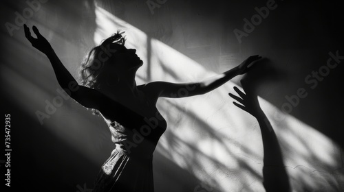 A graceful dancer radiates pure joy as she raises her arms to the beat of the music, casting a mesmerizing shadow in her elegant dress at a concert