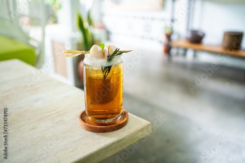 Fresh cold drink of lychee tea on a table with an elegant cafe in the background.