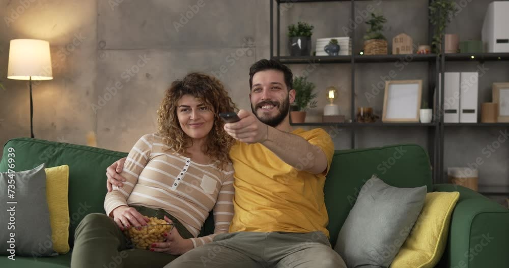 Couple caucasian man and woman sit at home on sofa bed watch tv movie Couple caucasian man and woman sit at home on sofa bed watch tv movie
